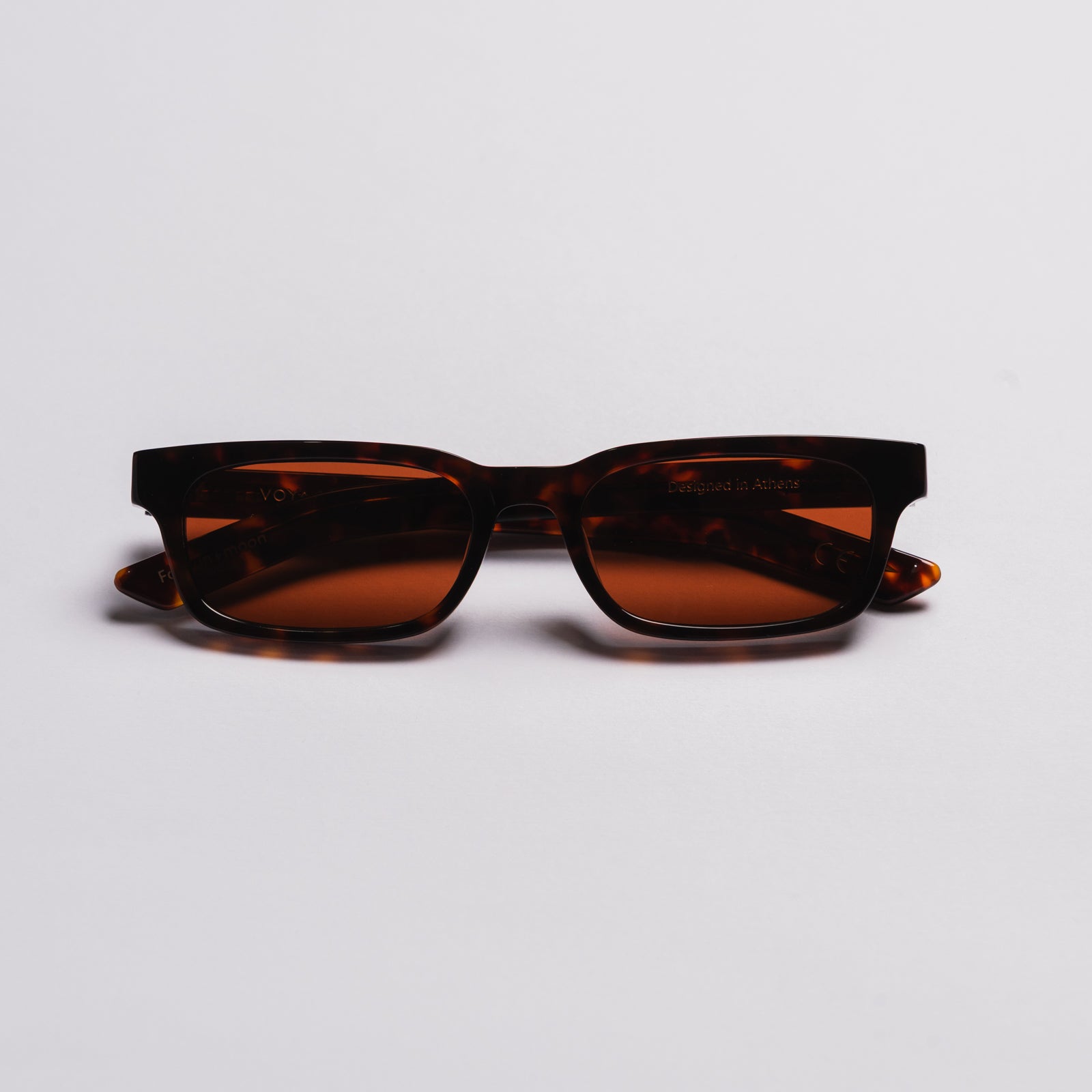 A pair of square-frame sunglasses with dark brown tortoiseshell frames and amber-brown tinted lenses, photographed on a clean light gray background.