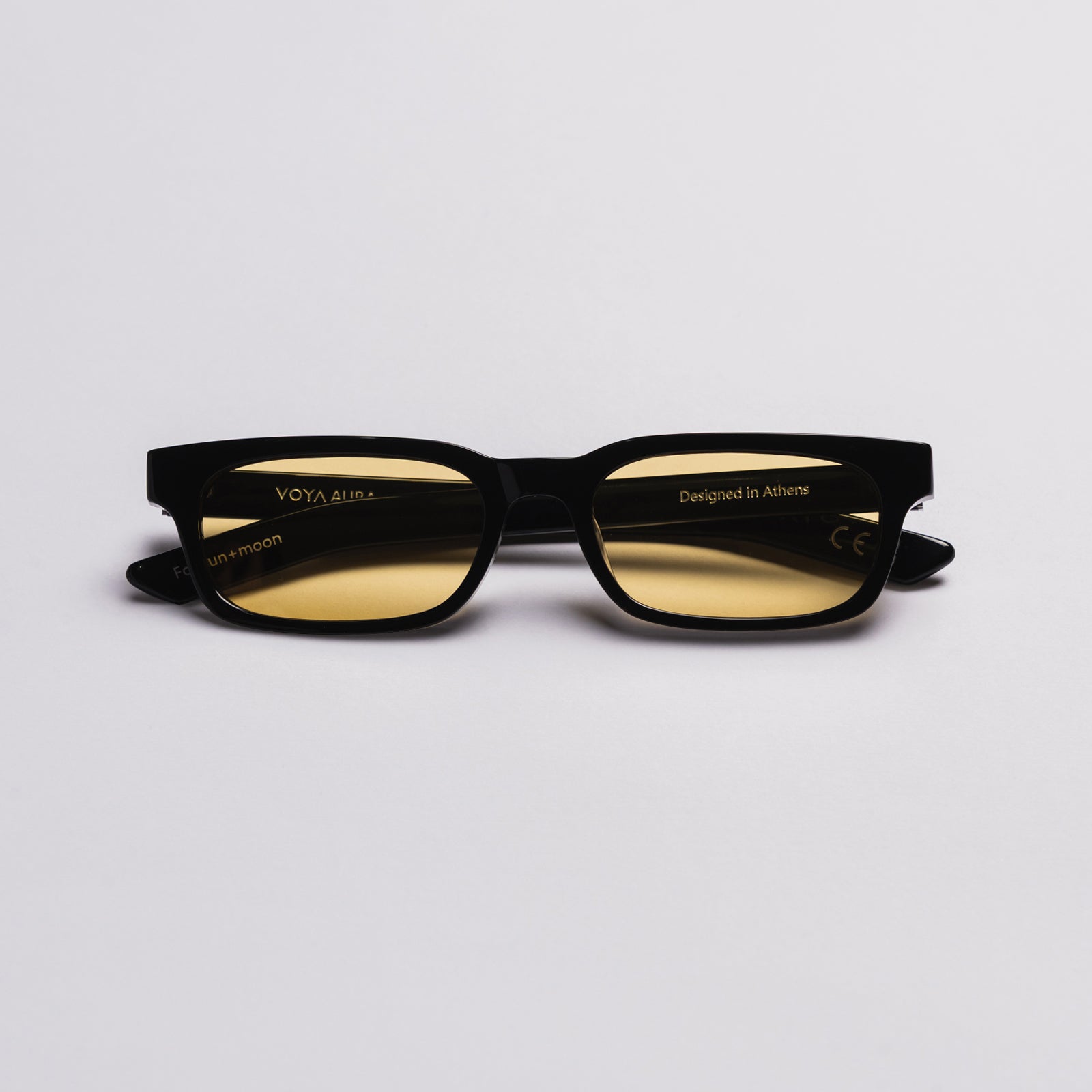 Black rectangular sunglasses with yellow tinted lenses, shown on a clean light gray background. The brand name 'VOYA' is visible on the temple arm.