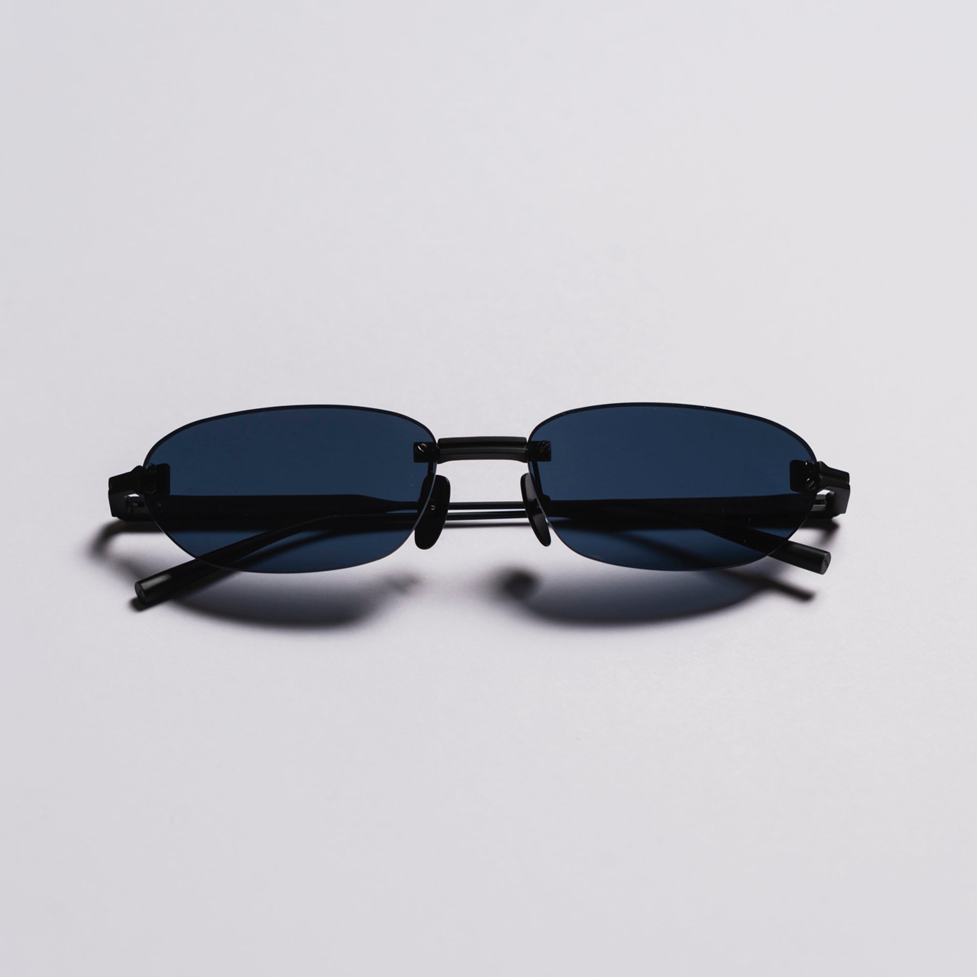 Black sunglasses with thin frame on a light gray background