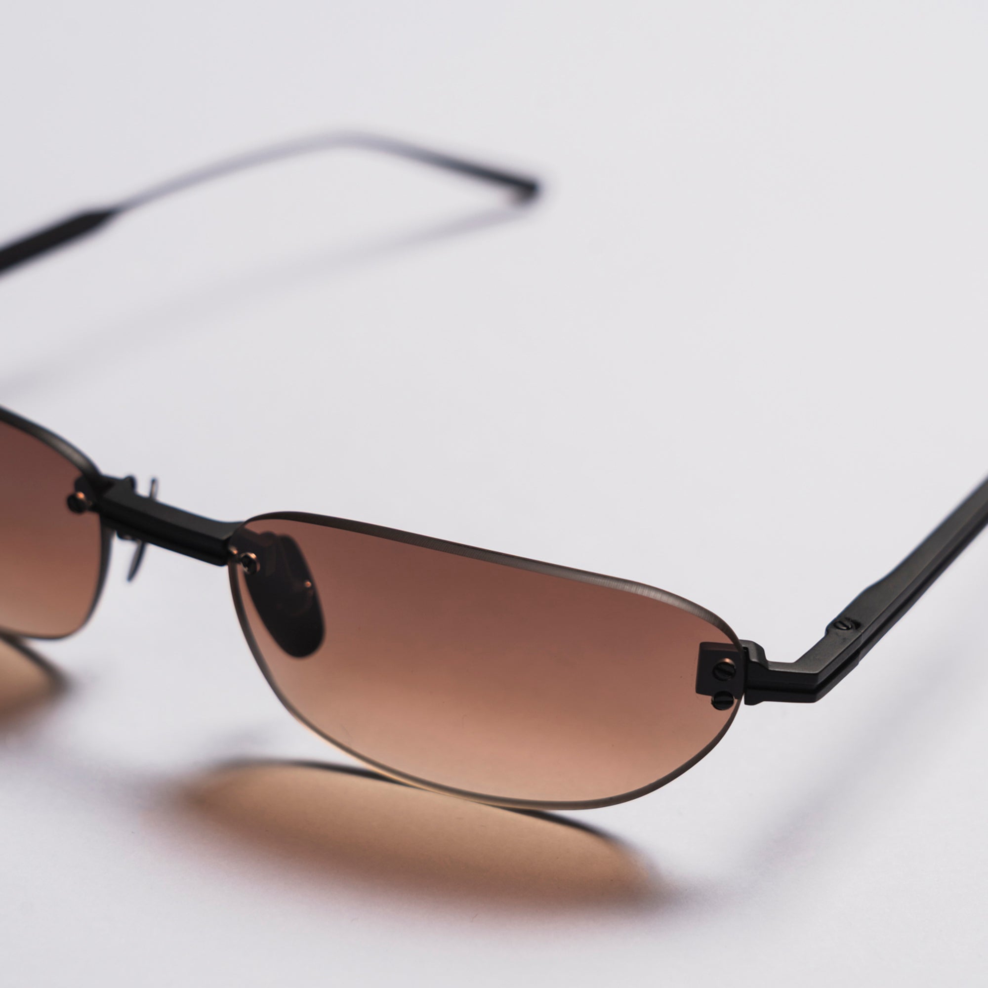 Sunglasses with brown lenses and black frames on a light gray background
