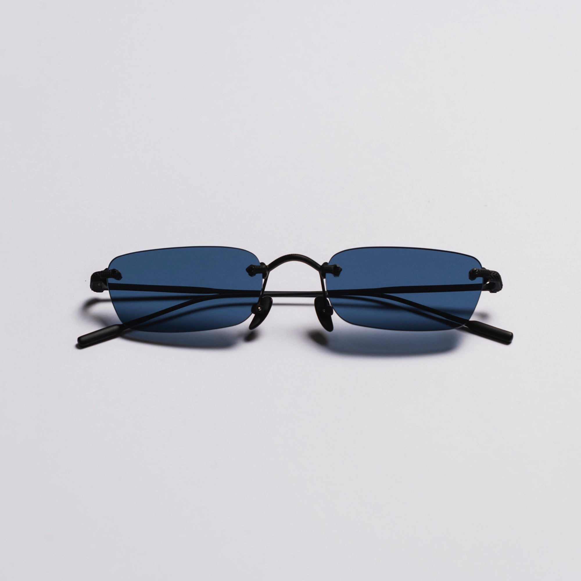 Sunglasses with black frame and blue lenses on a light gray background