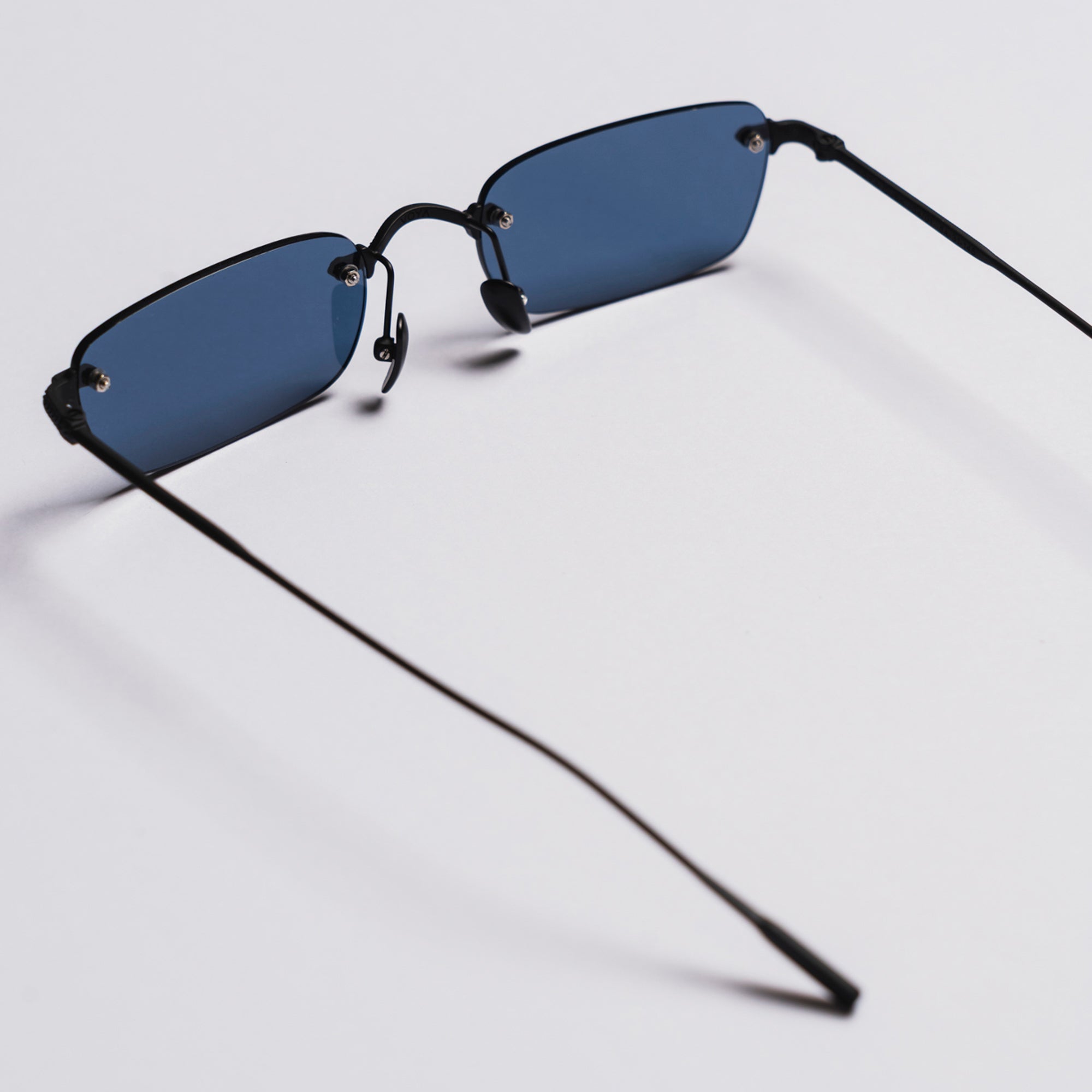 Sunglasses with black frame and blue lenses on a light gray background