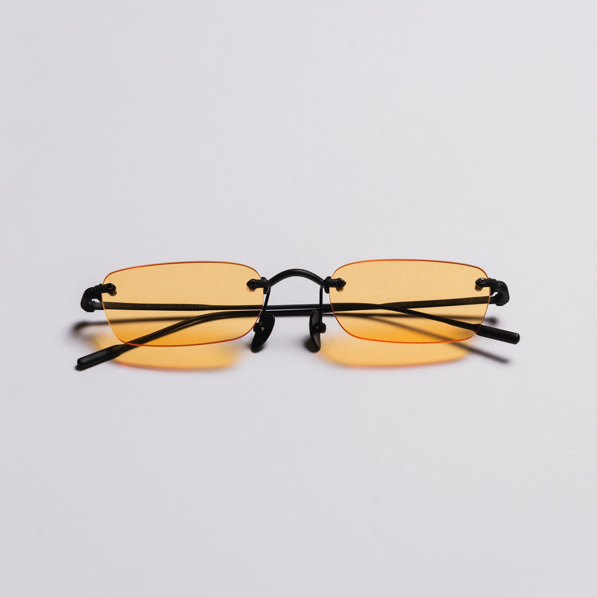 Yellow-tinted sunglasses with black frames on a light gray background