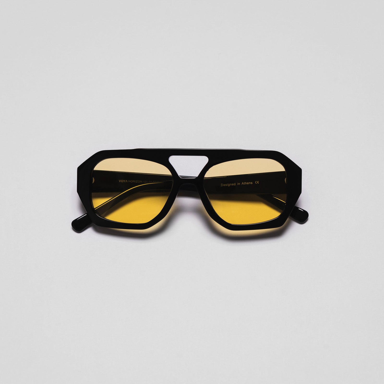 A pair of sunglasses with black frames and yellow tinted lenses positioned against a white background.
