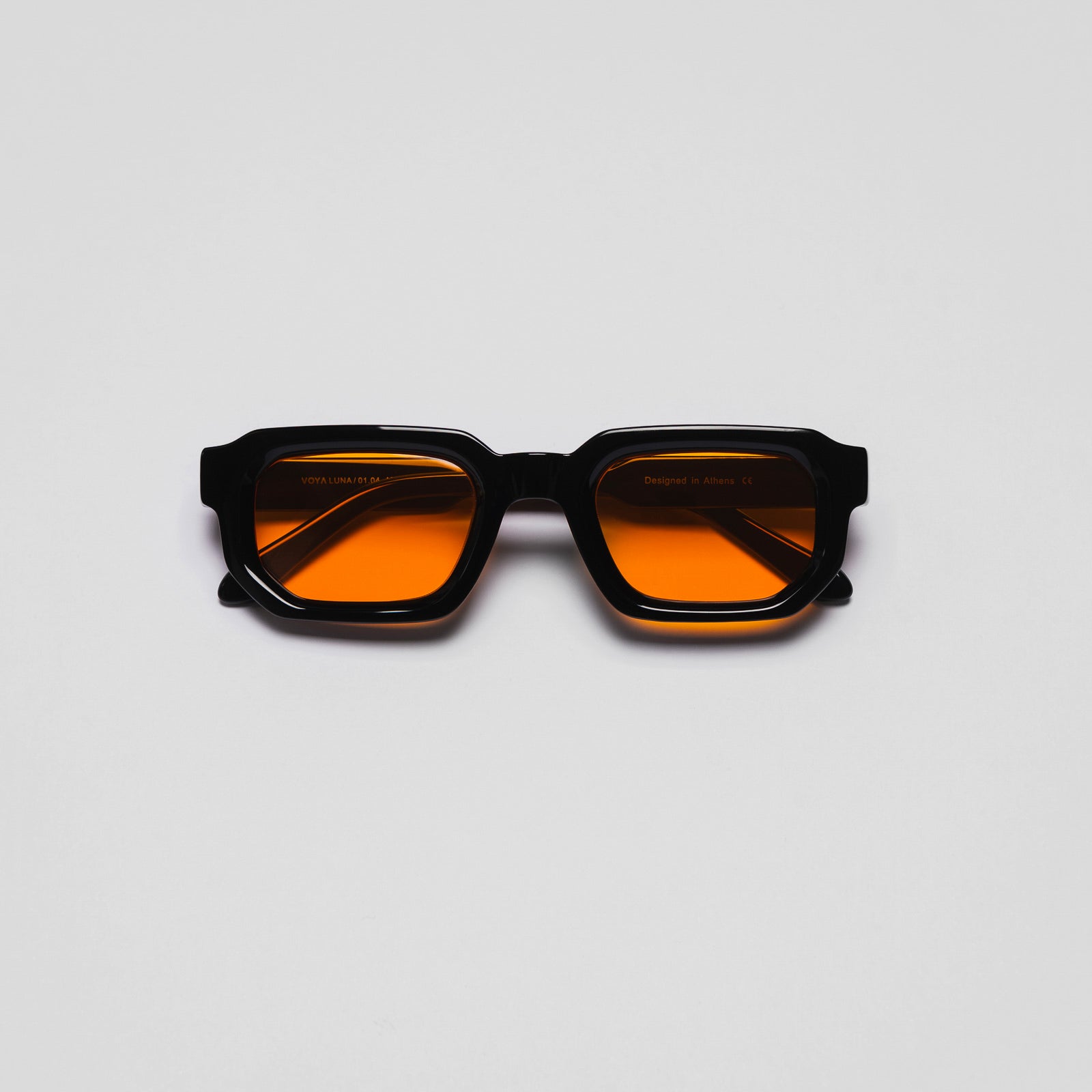 A pair of sunglasses with black frames and orange tinted lenses on a white background.