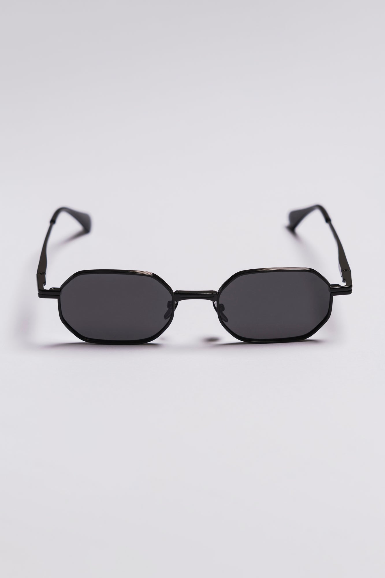 Black sunglasses with a hexagonal frame on a light gray background