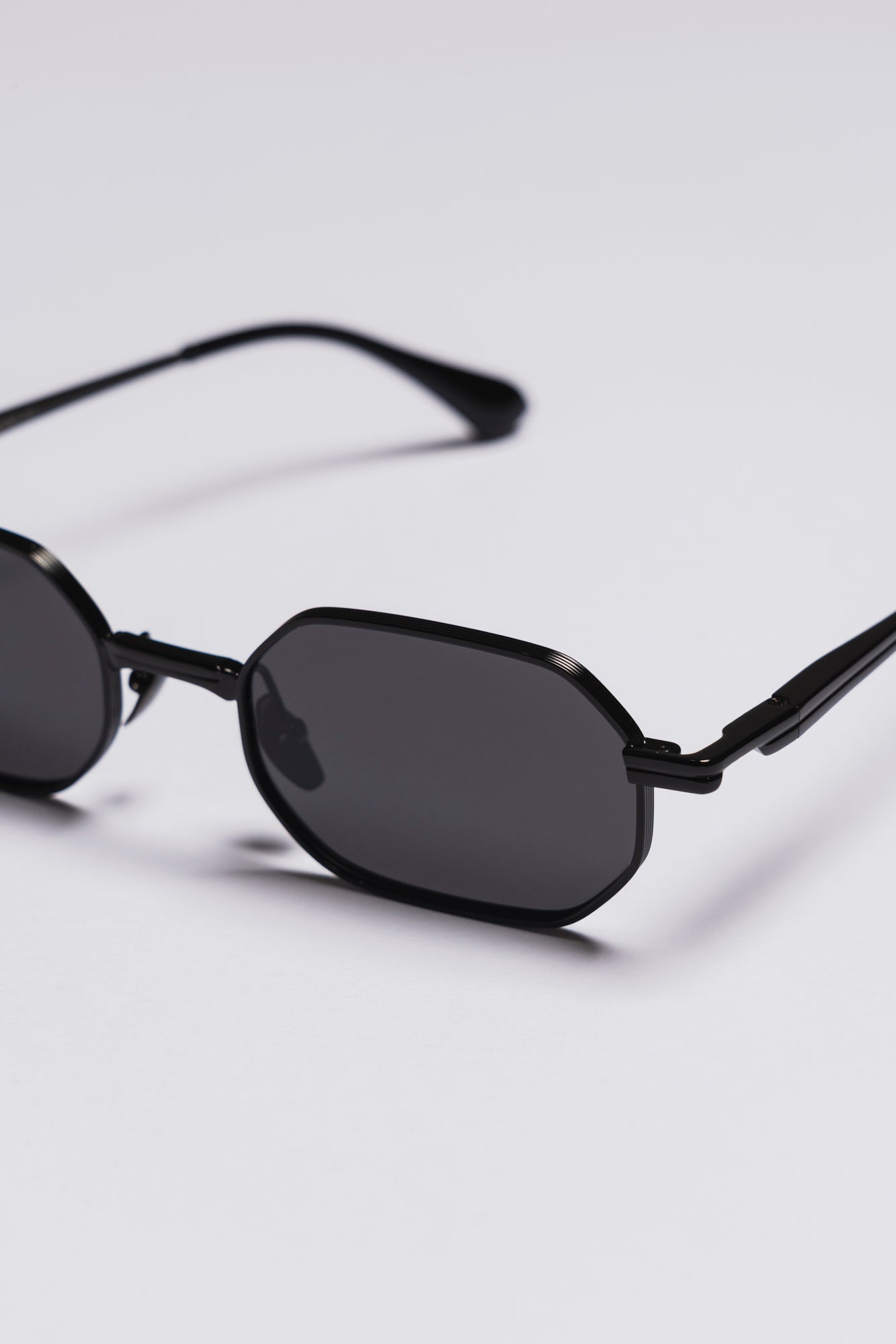 Black sunglasses with dark lenses on a light gray background