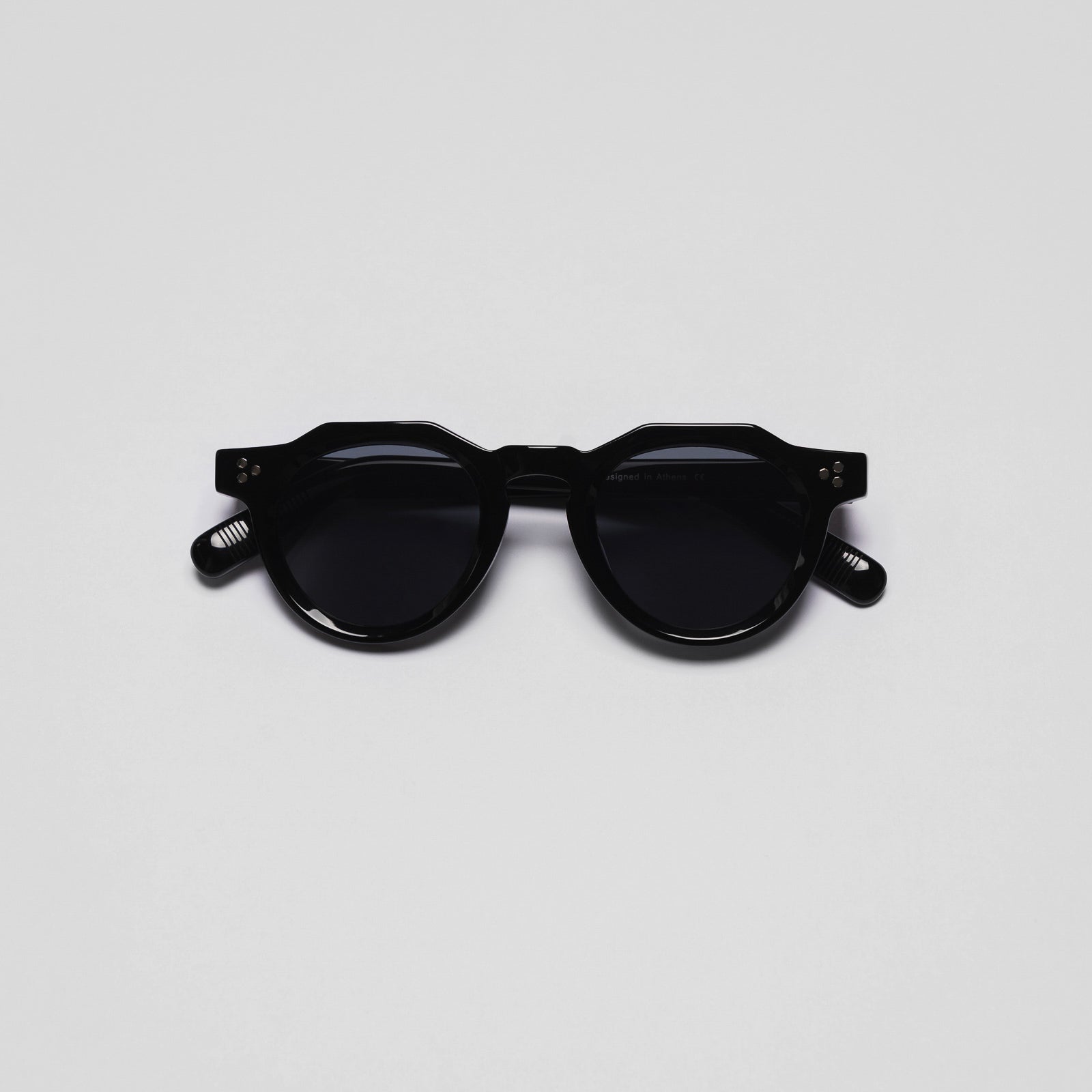 A pair of black sunglasses with a round shape and plastic frame.