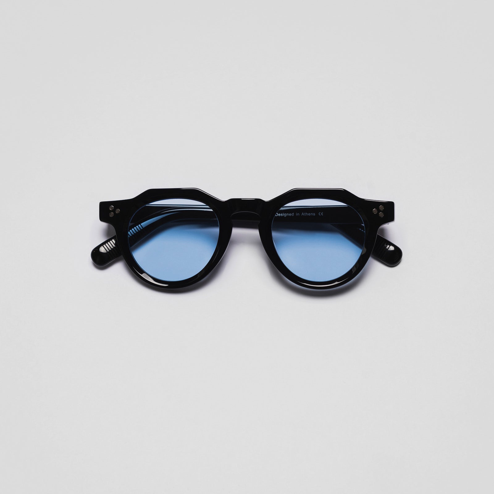 A pair of sunglasses with black frames and blue lenses on a white background.