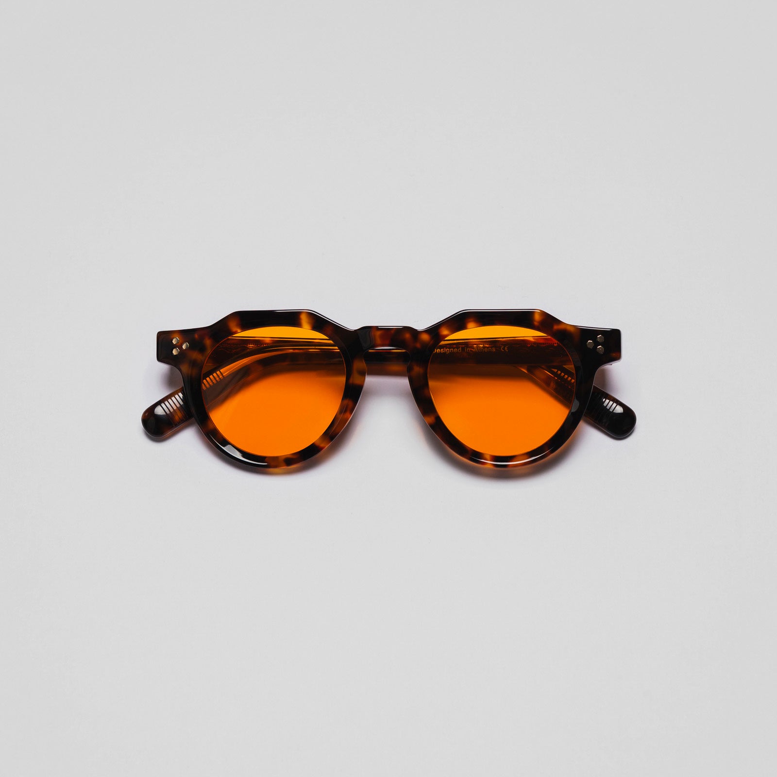 A pair of sunglasses with a round tortoiseshell pattern frame and orange lenses.