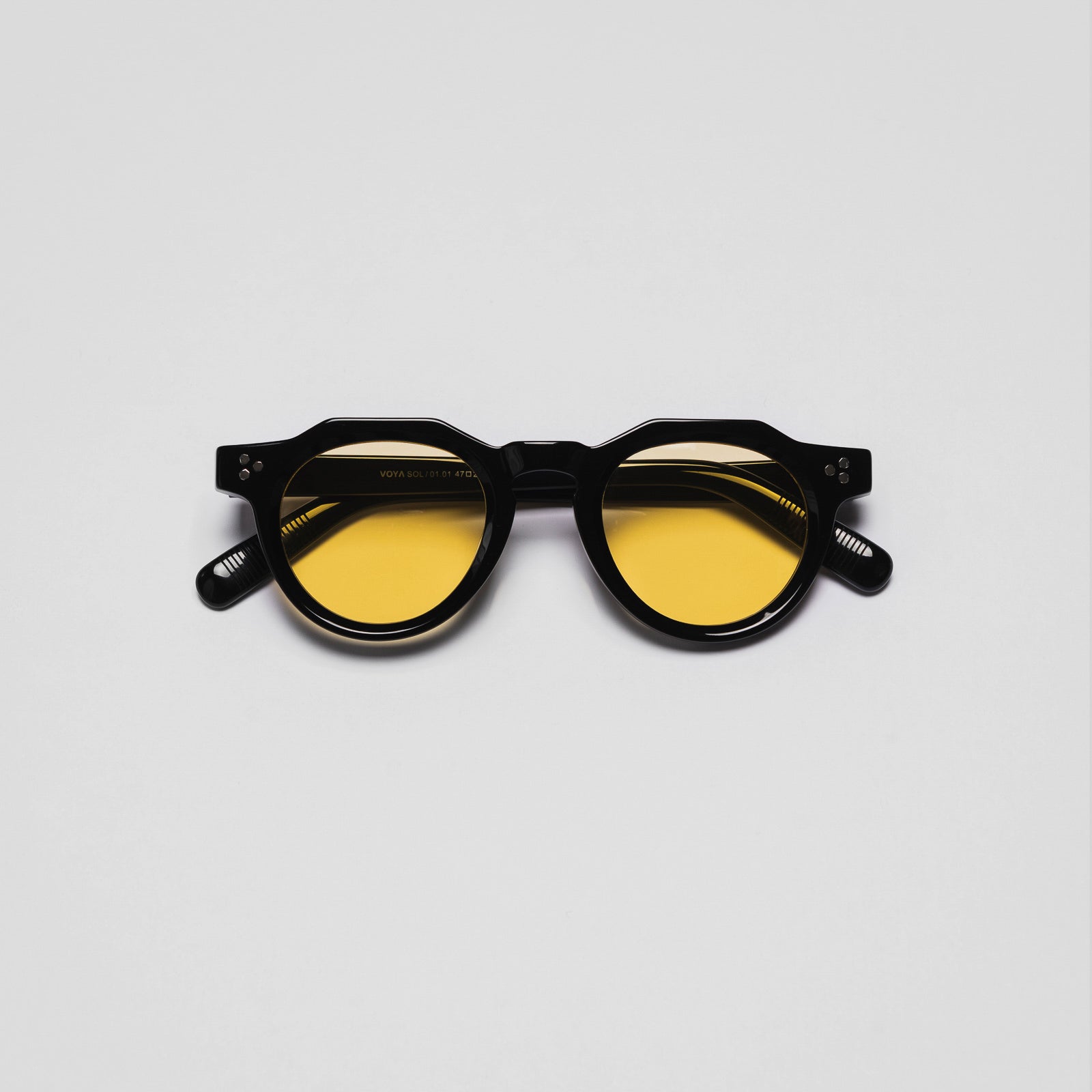 A pair of sunglasses with black frames and yellow tinted lenses on a white background.