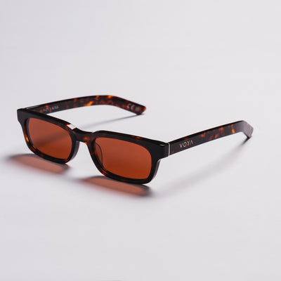 VOYA sunglasses with a dark brown and black tortoiseshell acetate frame and amber-brown tinted lenses, displayed on a clean light gray background.