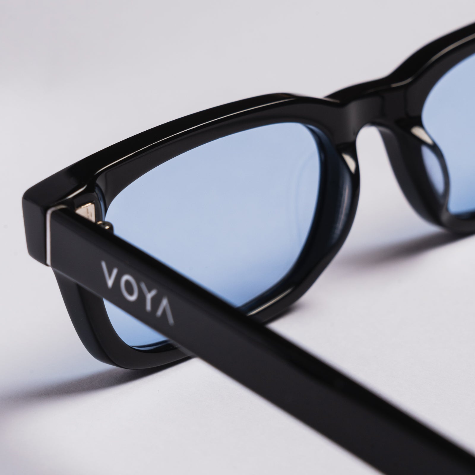 Close-up of black VOYA eyeglasses with light blue lenses on a clean white background.