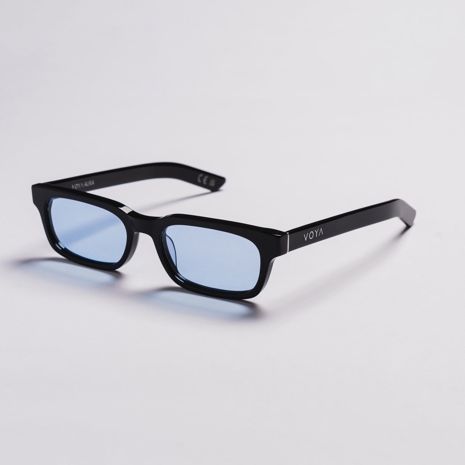 Black rectangular eyeglasses with light blue tinted lenses, shown on a clean light gray background. The brand name 'VOYA' is visible on the temple arm.