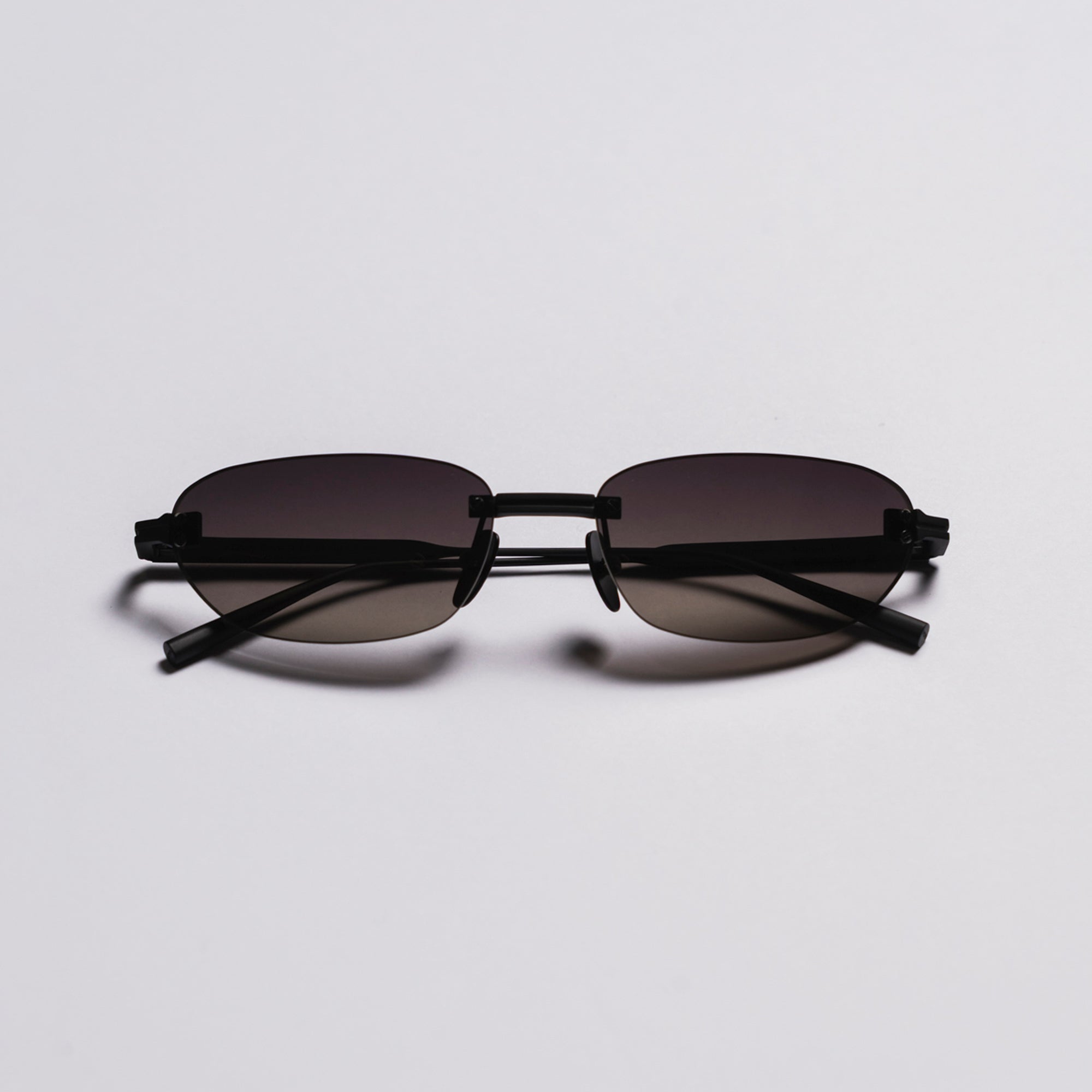 Black sunglasses with dark lenses on a light gray background
