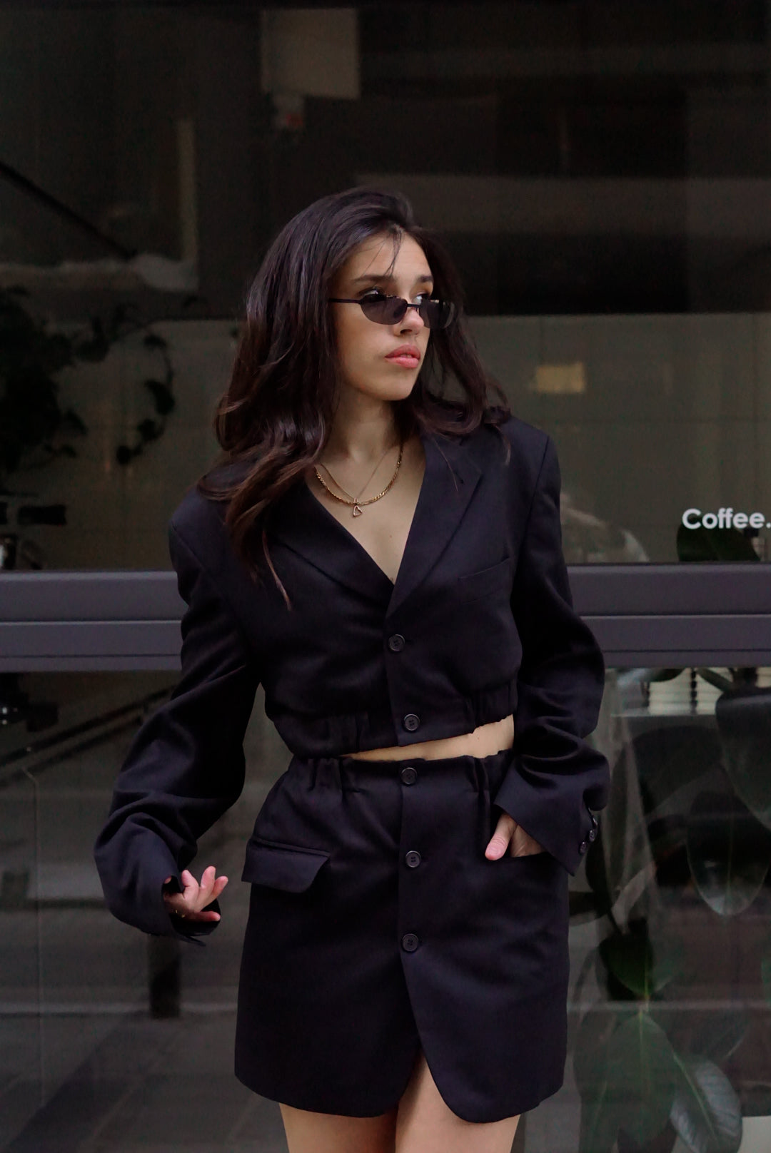 Woman in a black outfit standing in front of a glass window.