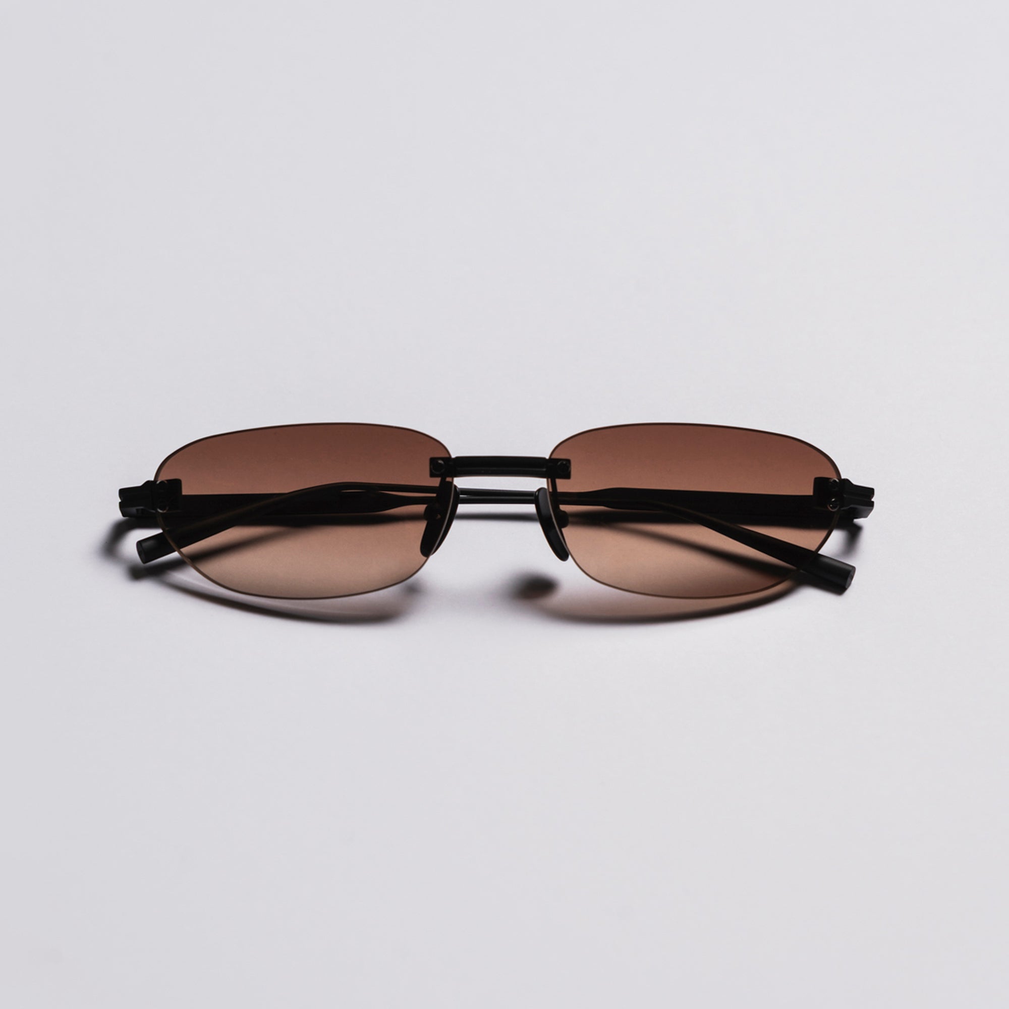 Sunglasses with brown lenses and black frames on a light gray background