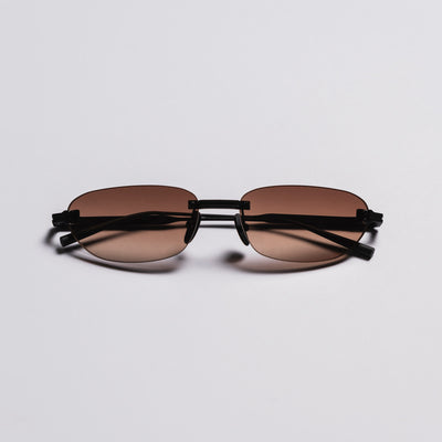 Sunglasses with brown lenses and black frames on a light gray background