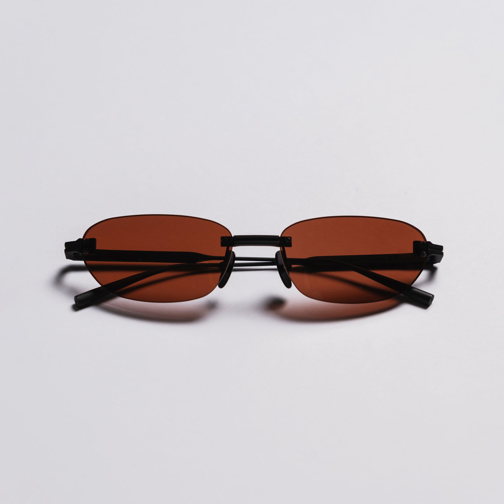 Sunglasses with brown lenses and black frames on a light gray background