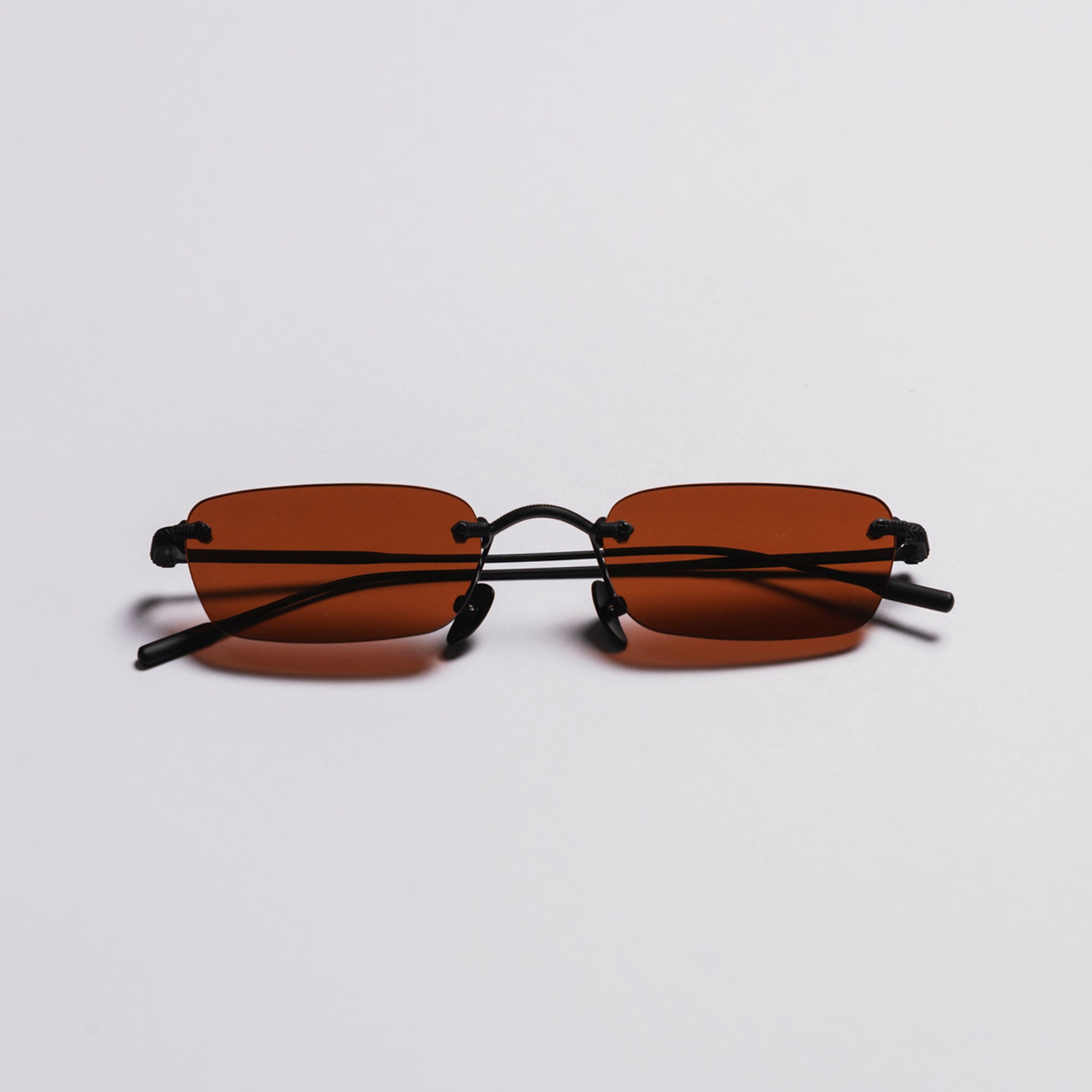 Sunglasses with red lenses and black frames on a light gray background