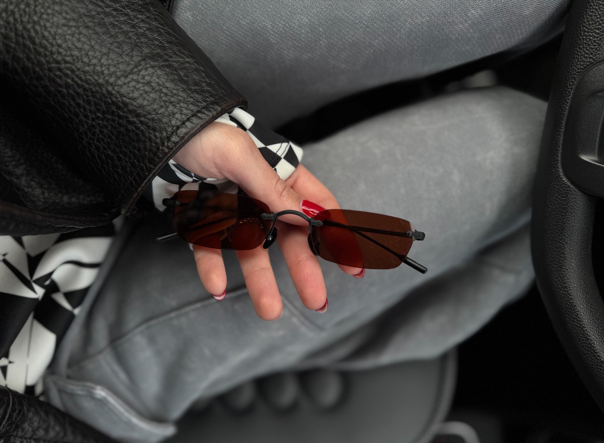 Person holding sunglasses with a car interior background