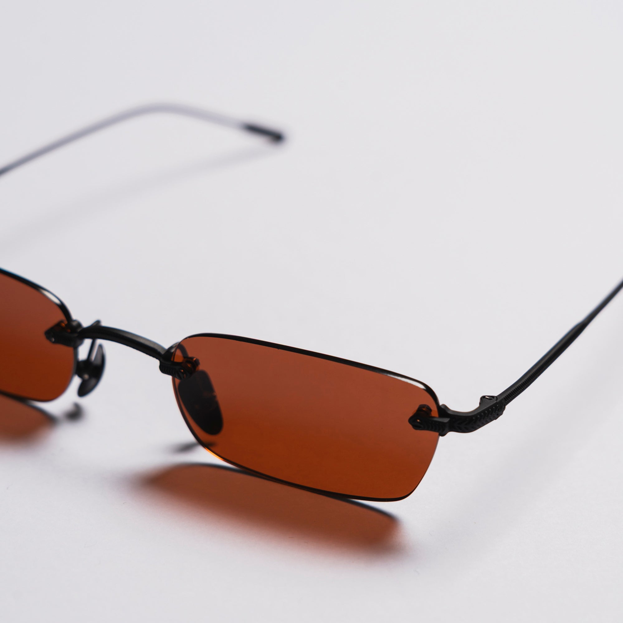 Sunglasses with brown lenses and black frames on a light gray background