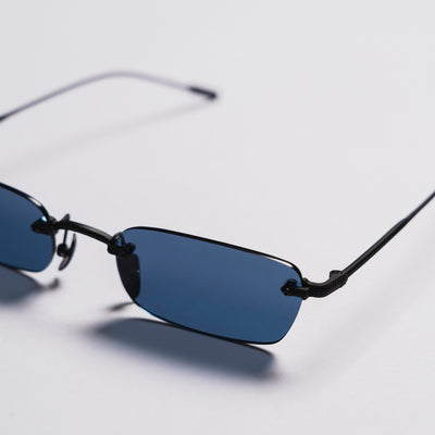 Sunglasses with blue lenses and thin black frames on a light gray background