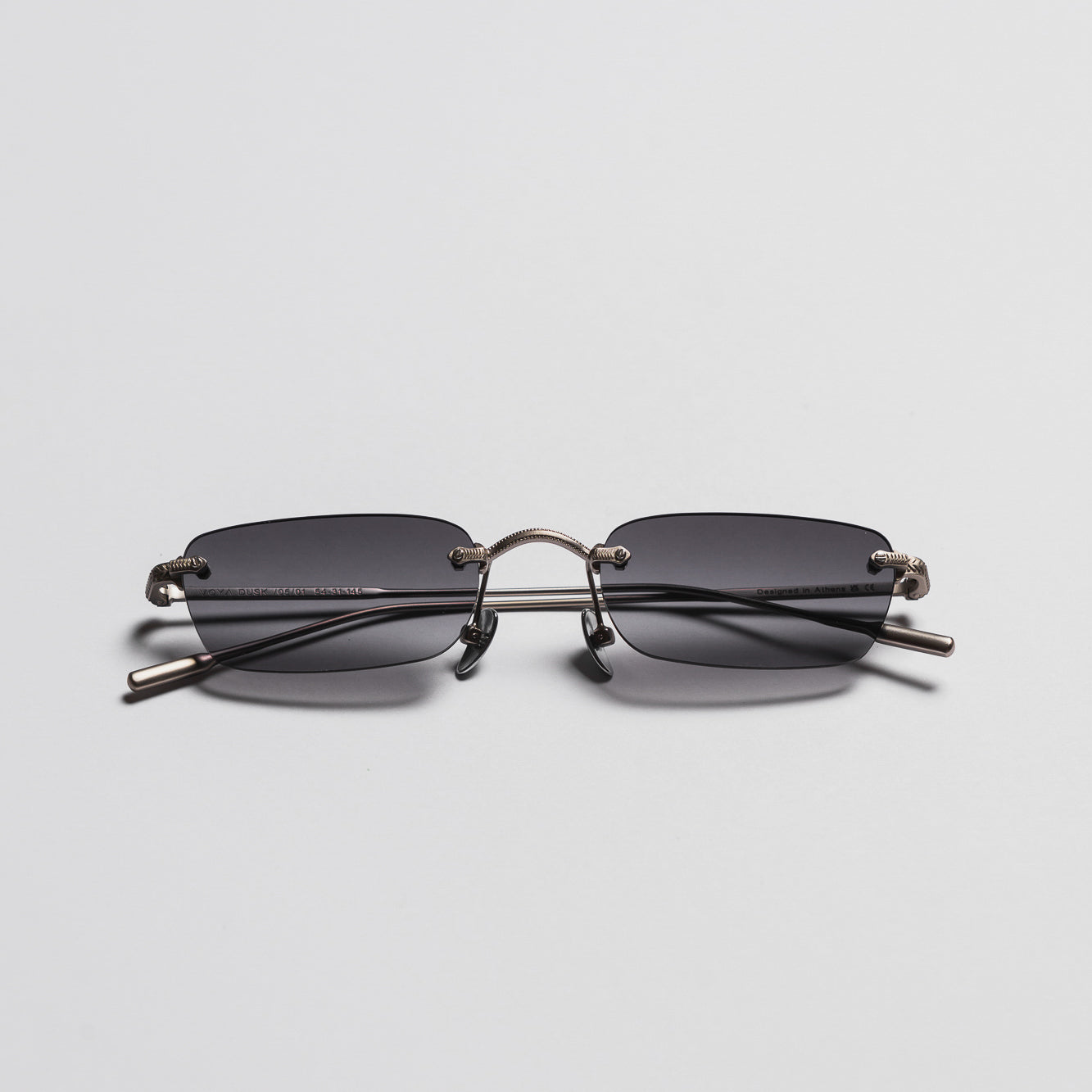 Sunglasses with a metallic frame and dark lenses on a light gray background