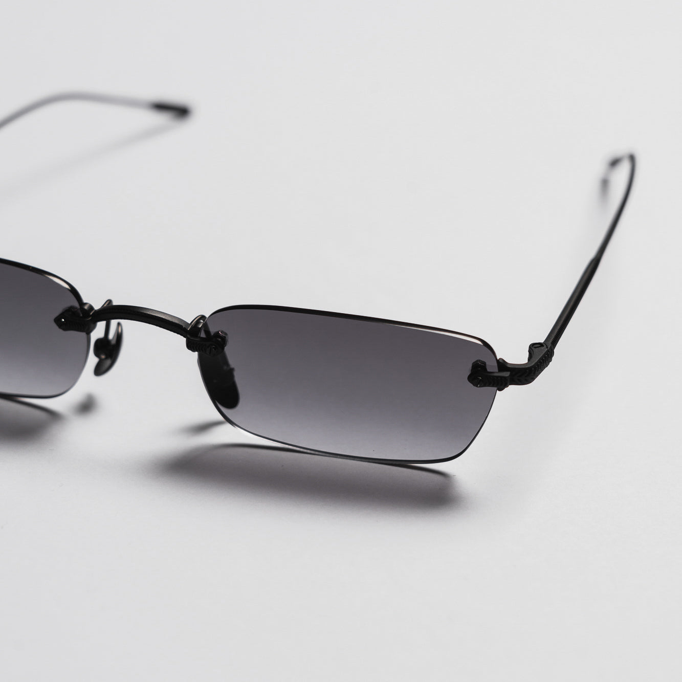 Sunglasses with black frames and gradient lenses on a light gray background