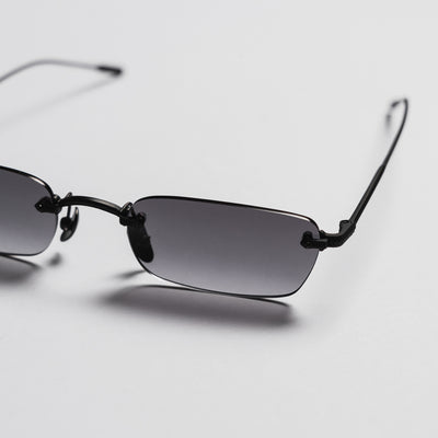 Sunglasses with black frames and gradient lenses on a light gray background