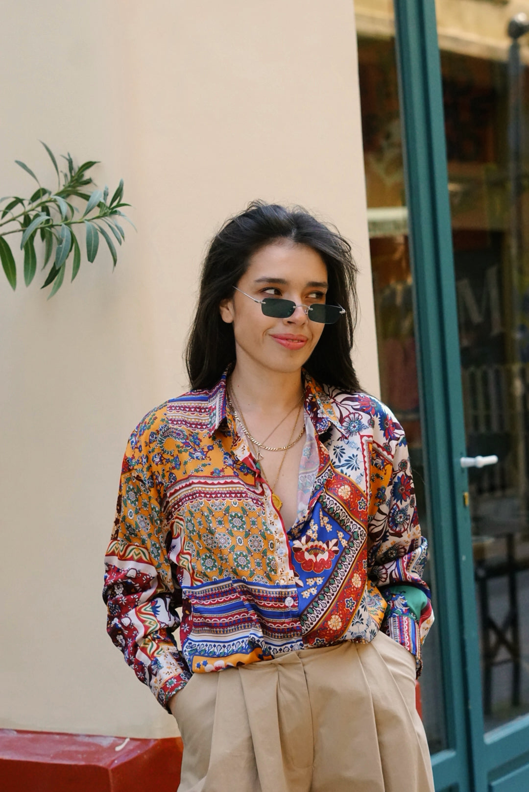 Woman wearing a colorful patterned shirt and sunglasses outdoors.