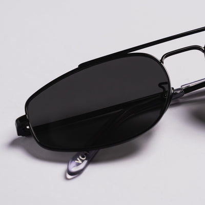 Black metal aviator-style sunglasses with dark tinted lenses, shown resting on a light gray surface.