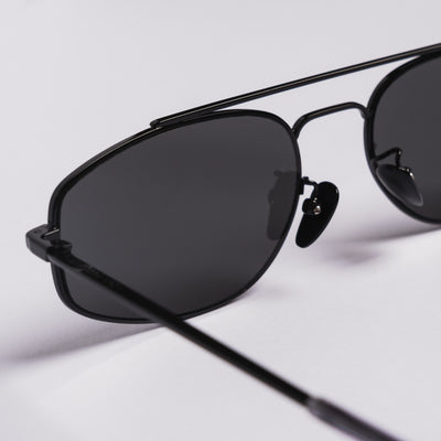 Close-up of black aviator-style sunglasses with dark lenses on a clean white background.