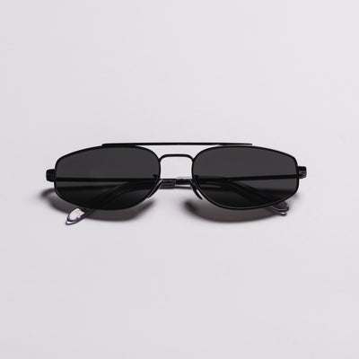 A pair of black aviator-style sunglasses with a double bridge and dark lenses, photographed on a clean light gray background.