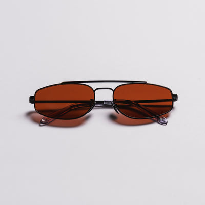 A pair of square aviator-style sunglasses with a black metal frame and warm brown tinted lenses, photographed from the front on a light gray background.