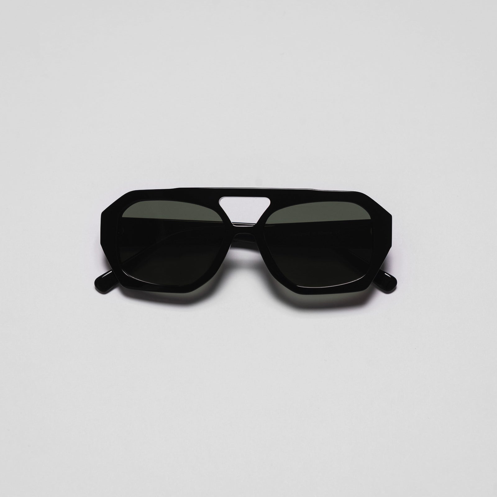 A pair of sunglasses with a black frame and dark lenses on a white background.