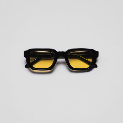 A pair of sunglasses with black frames and yellow tinted lenses.