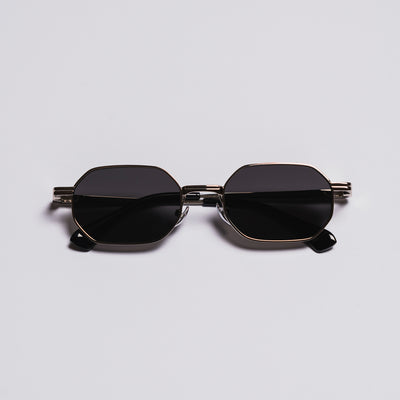 Sunglasses with black lenses and gold frame on a light gray background