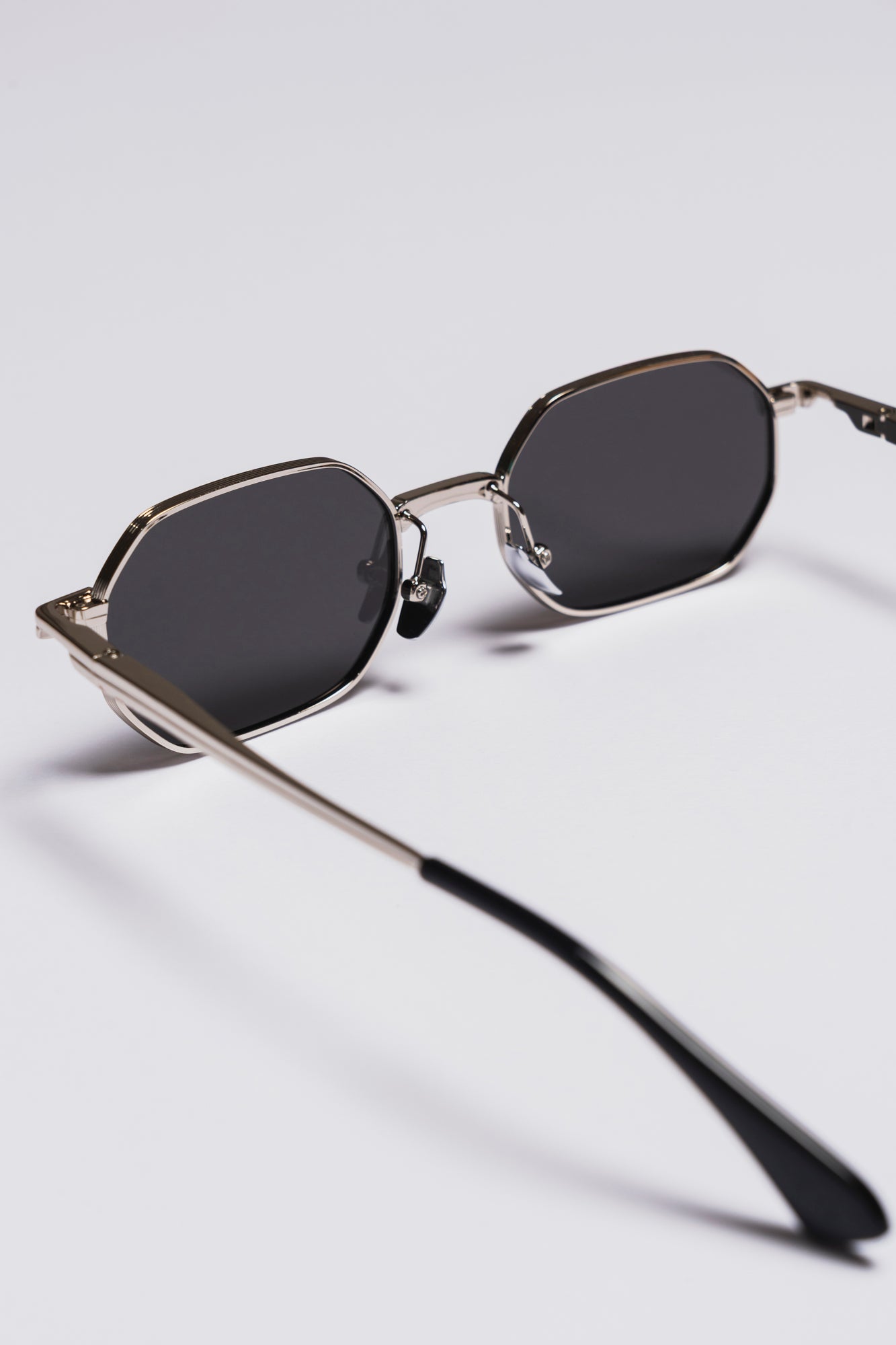 Sunglasses with dark lenses and thin metal frame on a light gray background