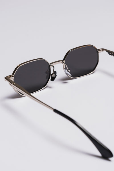 Sunglasses with dark lenses and thin metal frame on a light gray background