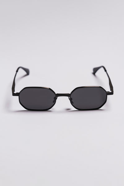 Black sunglasses with a hexagonal frame on a light gray background