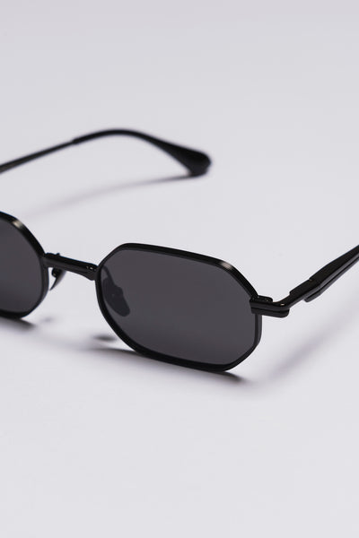 Black sunglasses with dark lenses on a light gray background