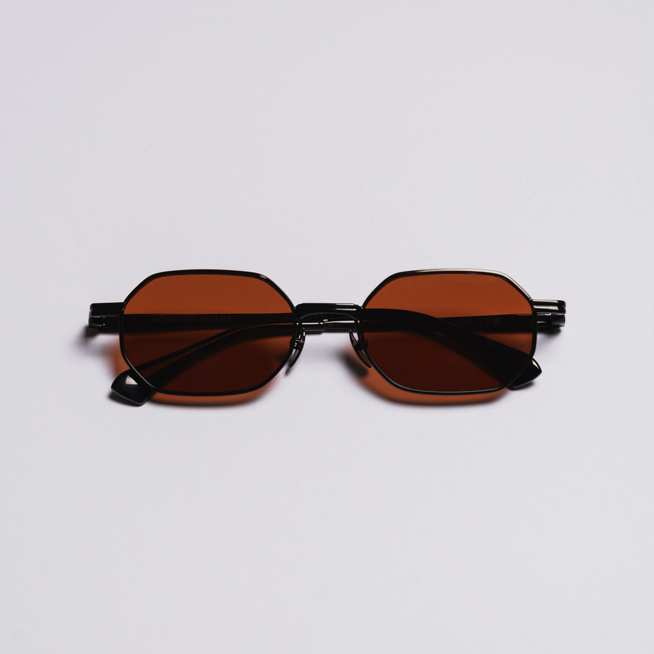 Sunglasses with brown lenses and black frames on a light gray background