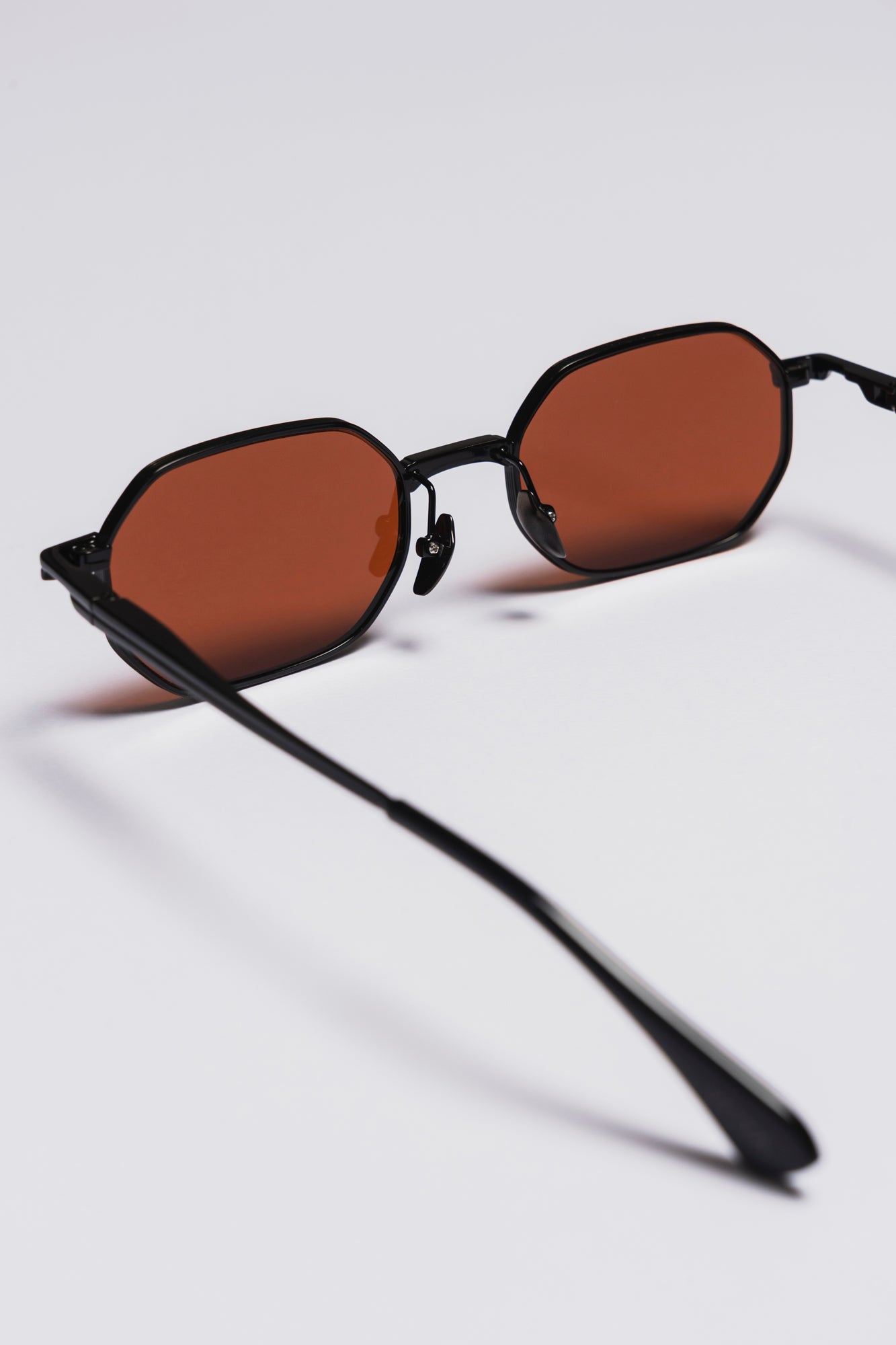Sunglasses with black frame and brown lenses on a light gray background
