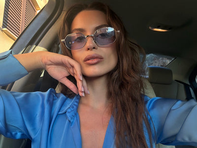 Woman wearing sunglasses and a blue shirt inside a car