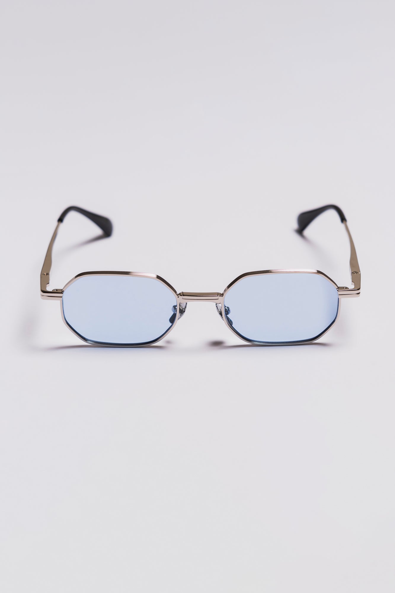sunglasses with a silver frame and blue lenses on a light gray background