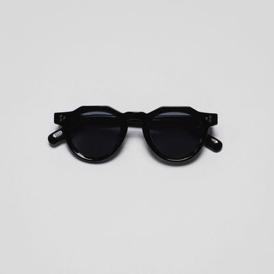 A pair of black sunglasses with a round shape and plastic frame.