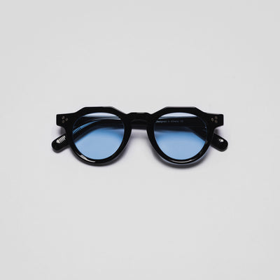 A pair of sunglasses with black frames and blue lenses on a white background.